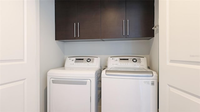 clothes washing area with cabinets and separate washer and dryer