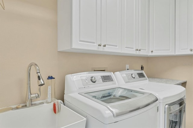 laundry area featuring cabinets, separate washer and dryer, and sink