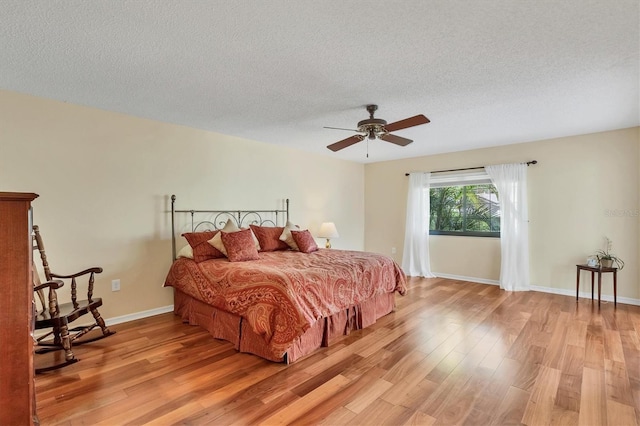 bedroom featuring ceiling fan, a textured ceiling, and light hardwood / wood-style floors