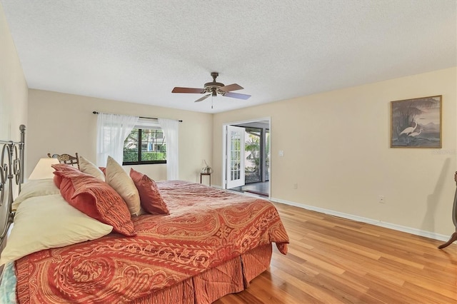 bedroom featuring ceiling fan, access to outside, a textured ceiling, and light wood-type flooring