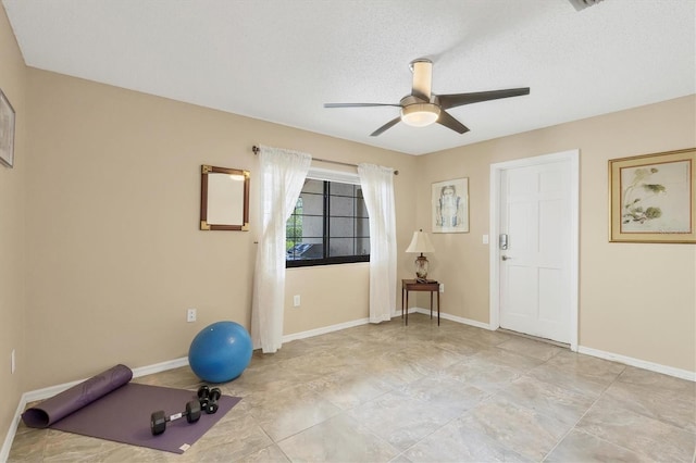 exercise room featuring ceiling fan and a textured ceiling