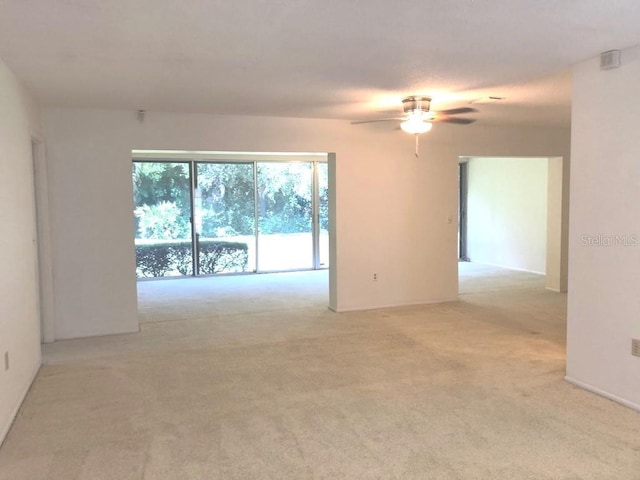 empty room featuring ceiling fan and light colored carpet