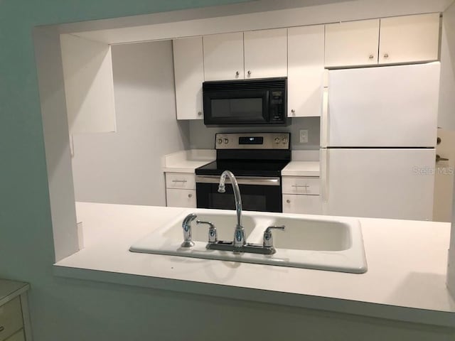 kitchen with electric range, white fridge, white cabinetry, and sink