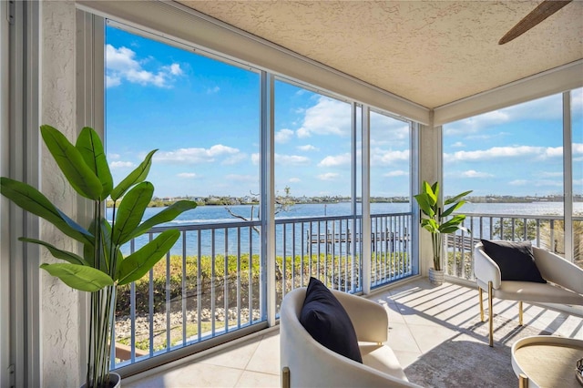 sunroom / solarium with plenty of natural light, ceiling fan, and a water view