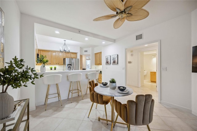 tiled dining room with ceiling fan with notable chandelier