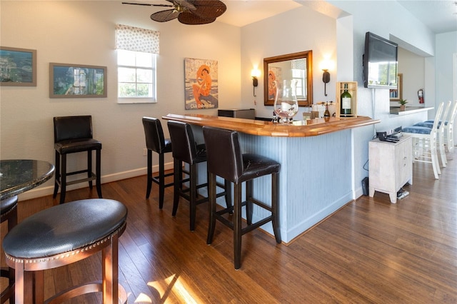 bar with dark hardwood / wood-style flooring, ceiling fan, and butcher block counters