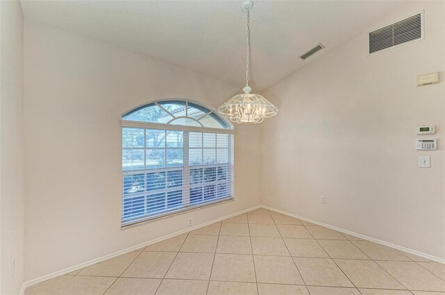 tiled empty room with lofted ceiling and an inviting chandelier