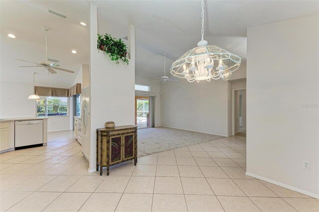 tiled dining area with high vaulted ceiling and ceiling fan with notable chandelier