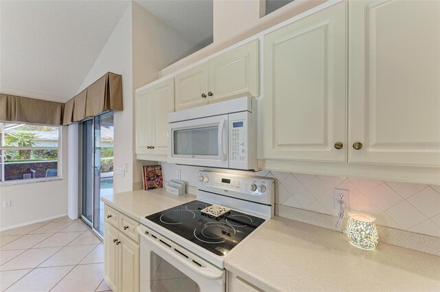 kitchen featuring vaulted ceiling, tasteful backsplash, light tile patterned flooring, and white appliances