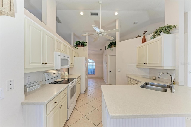 kitchen with kitchen peninsula, white appliances, sink, lofted ceiling, and light tile patterned flooring