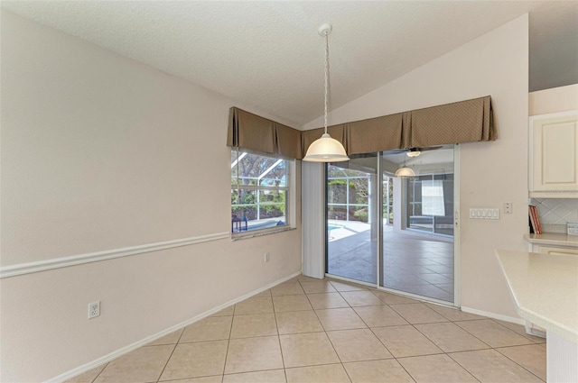 unfurnished dining area featuring light tile patterned floors and vaulted ceiling