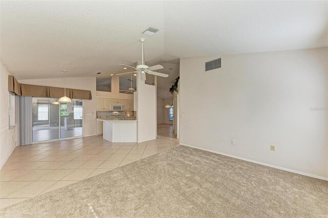 unfurnished living room with ceiling fan, light tile patterned floors, and vaulted ceiling