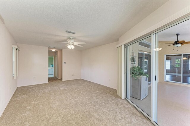 carpeted empty room with ceiling fan and a textured ceiling