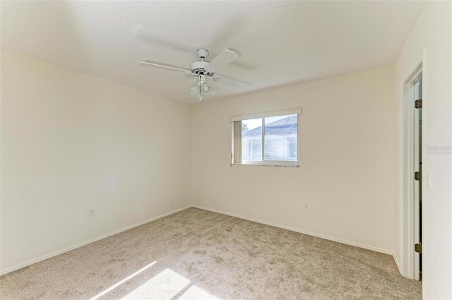 carpeted spare room featuring ceiling fan