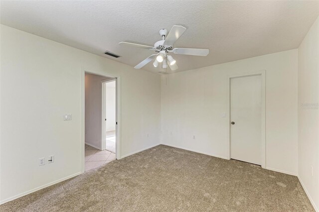 empty room featuring light carpet, a textured ceiling, and ceiling fan