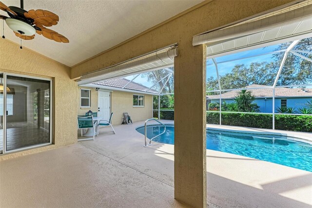 view of pool with glass enclosure, ceiling fan, and a patio area