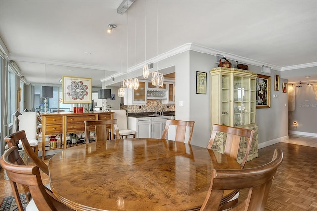 dining room with crown molding, sink, and light parquet flooring