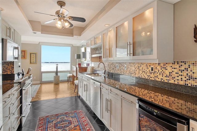 kitchen featuring white cabinetry, sink, dark tile patterned floors, stainless steel dishwasher, and a water view