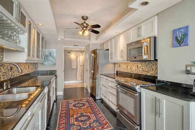 kitchen with dark stone counters, dark tile patterned flooring, a raised ceiling, white cabinetry, and stainless steel appliances