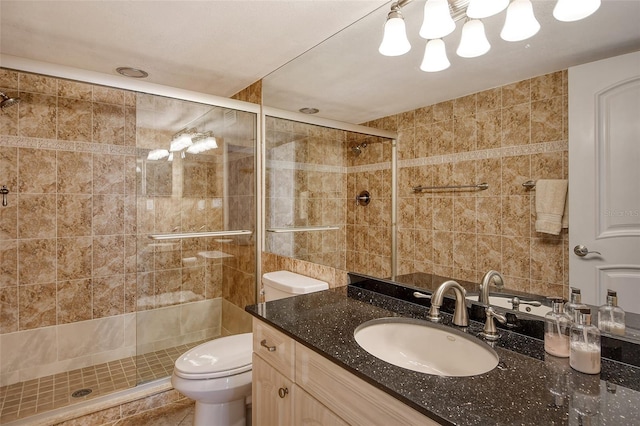 bathroom featuring toilet, vanity, tile walls, and walk in shower