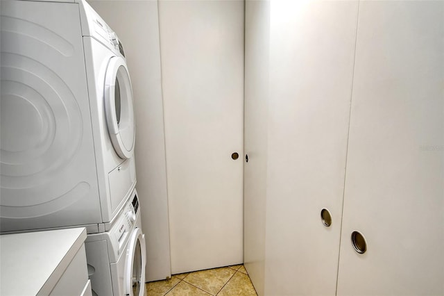 clothes washing area featuring light tile patterned floors and stacked washer and dryer