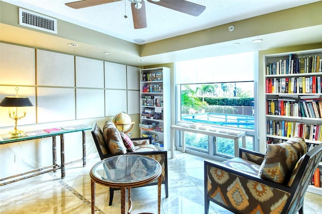 living area featuring light tile patterned floors, a textured ceiling, and ceiling fan