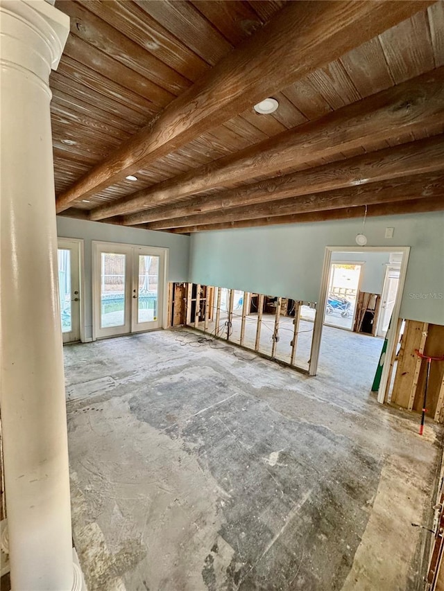 unfurnished room with wooden ceiling, a wealth of natural light, beam ceiling, and french doors