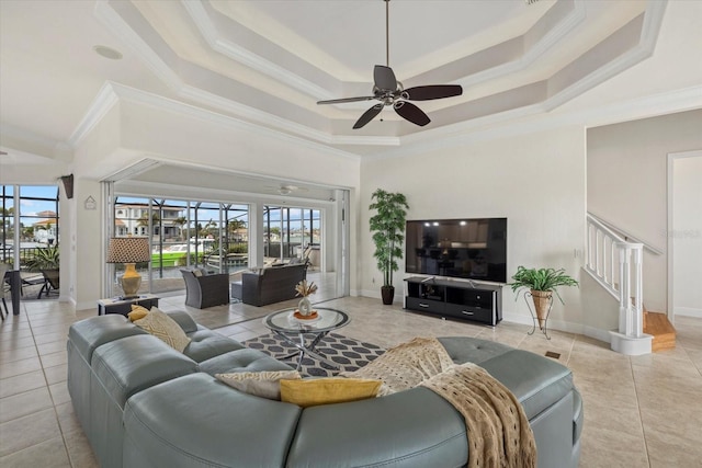 tiled living room featuring a tray ceiling, a wealth of natural light, and ceiling fan