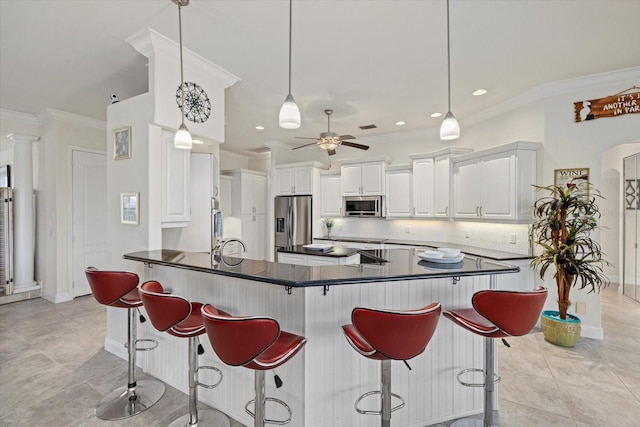 kitchen featuring appliances with stainless steel finishes, decorative light fixtures, a breakfast bar, white cabinets, and ornamental molding