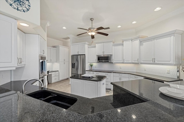 kitchen featuring dark stone counters, sink, appliances with stainless steel finishes, tasteful backsplash, and white cabinetry