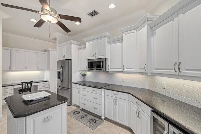 kitchen with stainless steel appliances, a kitchen island, tasteful backsplash, white cabinets, and ornamental molding