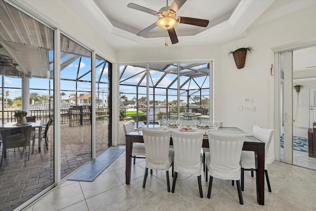 sunroom / solarium with a water view, ceiling fan, and a tray ceiling