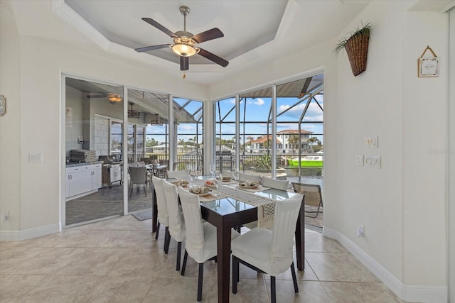 tiled dining space featuring a tray ceiling and ceiling fan