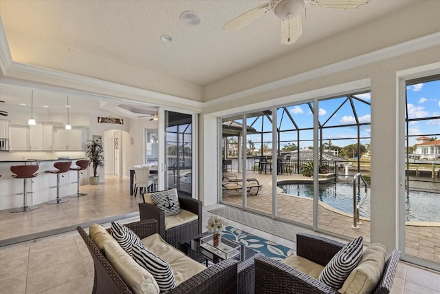 sunroom featuring ceiling fan and a water view