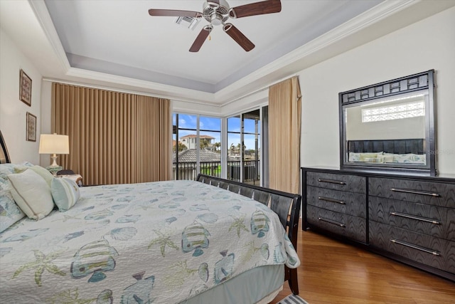 bedroom with hardwood / wood-style floors, a tray ceiling, and ceiling fan