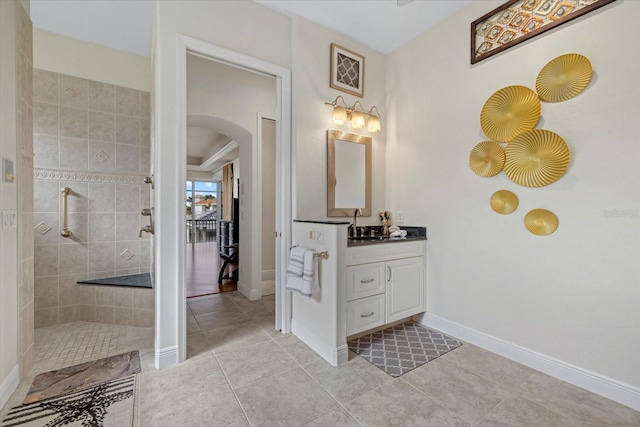 bathroom featuring a tile shower, tile patterned floors, and vanity