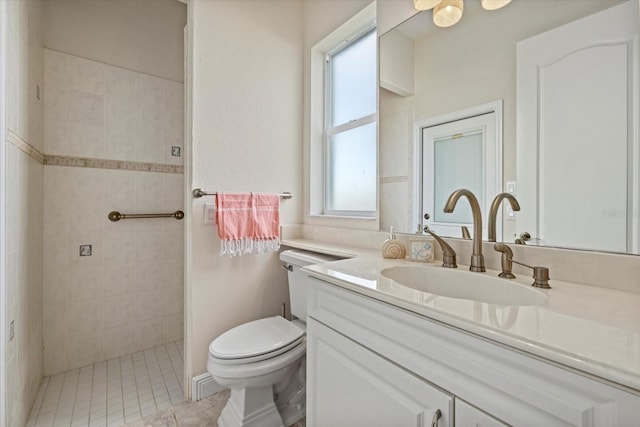 bathroom featuring a tile shower, plenty of natural light, vanity, and toilet