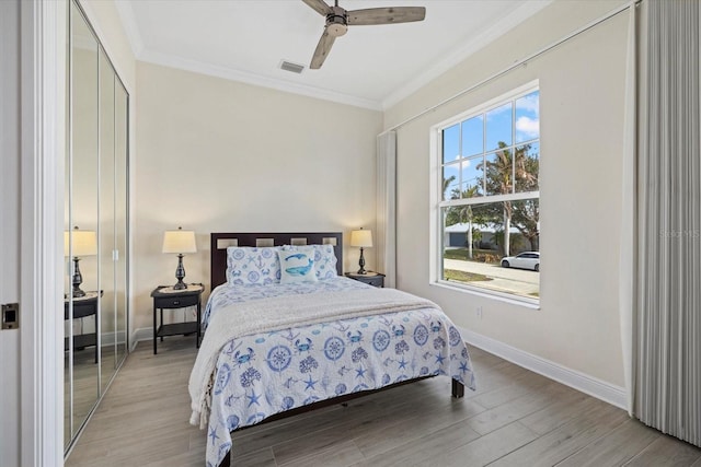 bedroom featuring multiple windows, light wood-type flooring, ceiling fan, and crown molding