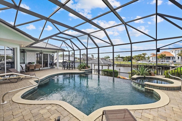 view of pool featuring glass enclosure, an in ground hot tub, a patio area, and a water view