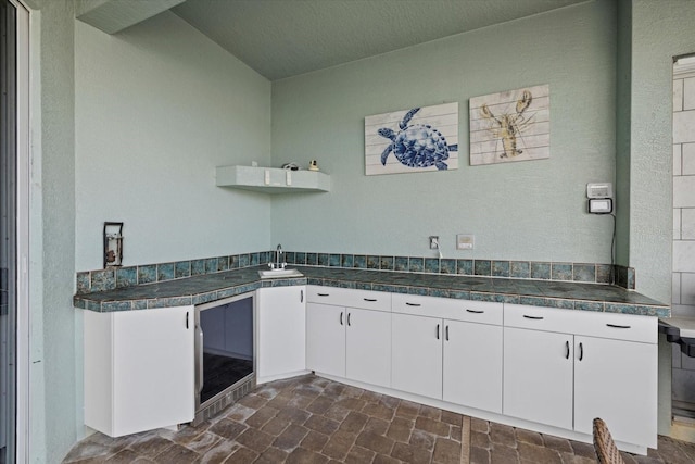 kitchen with white cabinets, sink, and wine cooler