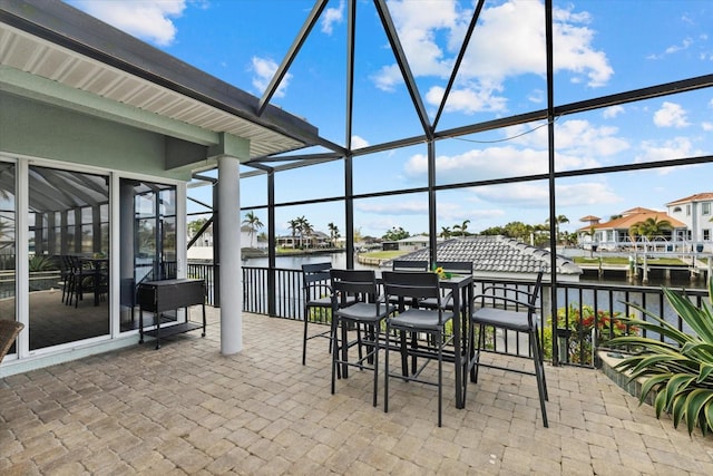 view of patio with a water view and a lanai