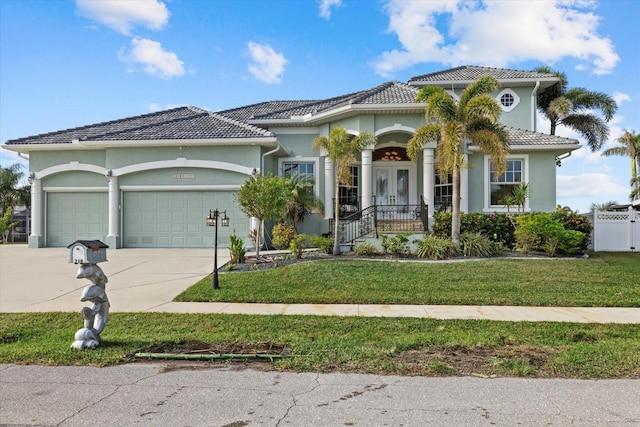 mediterranean / spanish-style home featuring a front lawn, a garage, covered porch, and french doors