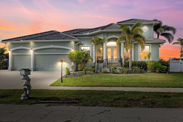 mediterranean / spanish-style home with a garage, a yard, and french doors