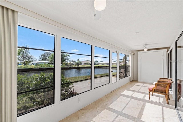 sunroom with ceiling fan and a water view