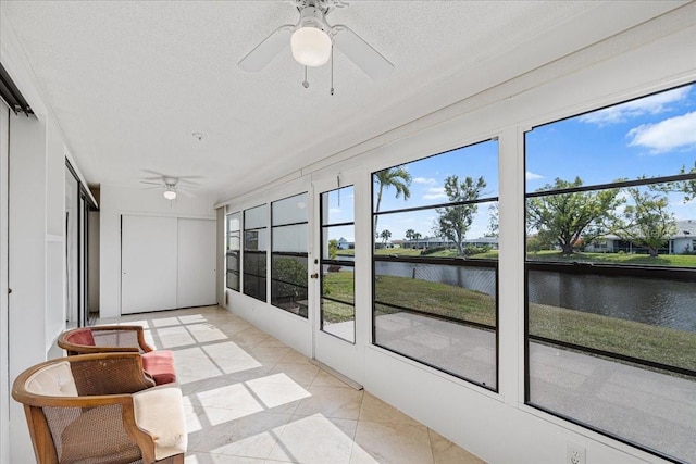 sunroom / solarium featuring ceiling fan and a water view