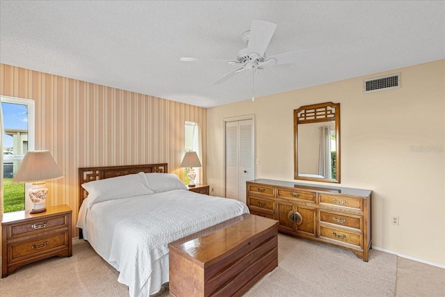 carpeted bedroom featuring a textured ceiling, a closet, and ceiling fan