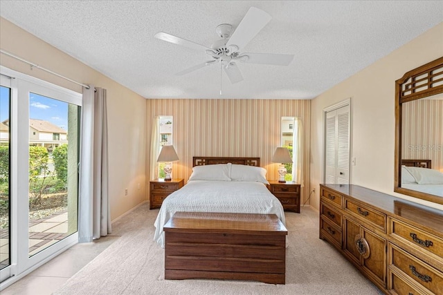 carpeted bedroom with ceiling fan, access to exterior, a textured ceiling, and a closet