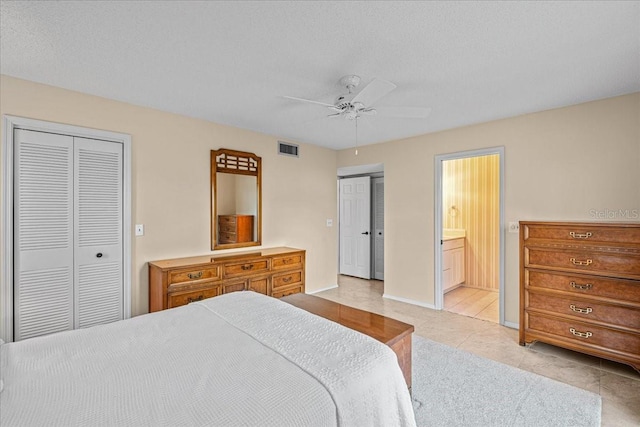 tiled bedroom featuring ceiling fan, ensuite bathroom, and a textured ceiling