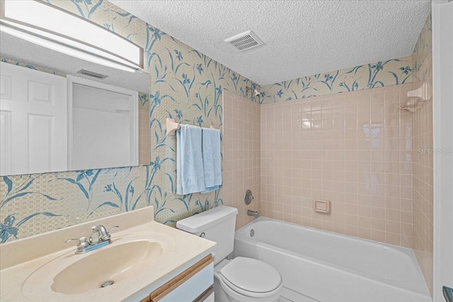 full bathroom featuring toilet, vanity, a textured ceiling, and tiled shower / bath