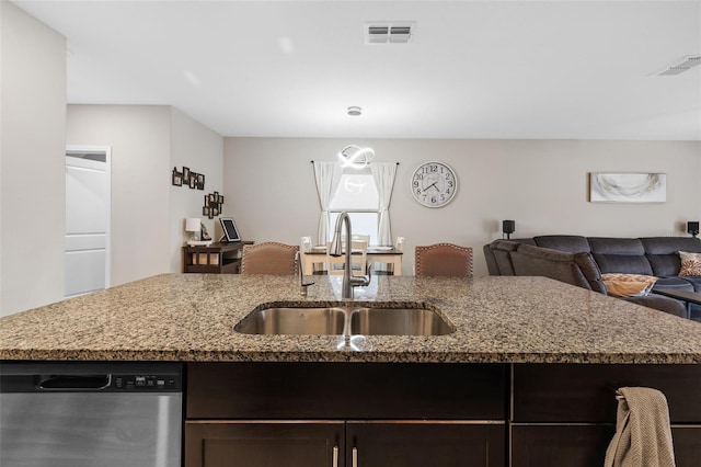 kitchen with light stone counters, dark brown cabinetry, dishwasher, and sink